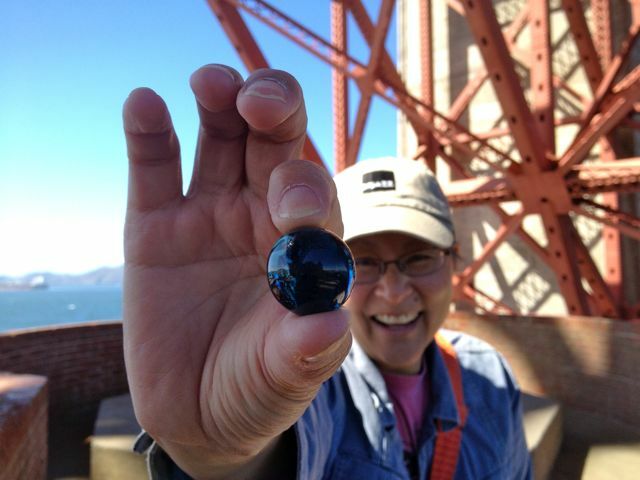 Andi Wong holding a blue marble on the Golden Gate Bridge