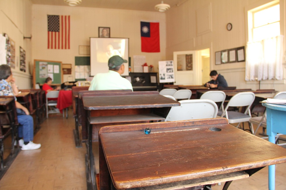 One blue marble sits in the pencil groove of the worn wooden school desk in the one room schoolhouse where visitors gather for the celebration of the the town of Locke's 100th birthday. On the far wall, a framed photo of Dr. Sun Yat-Sen hangs between an American flag and the flag of the Republic of China.