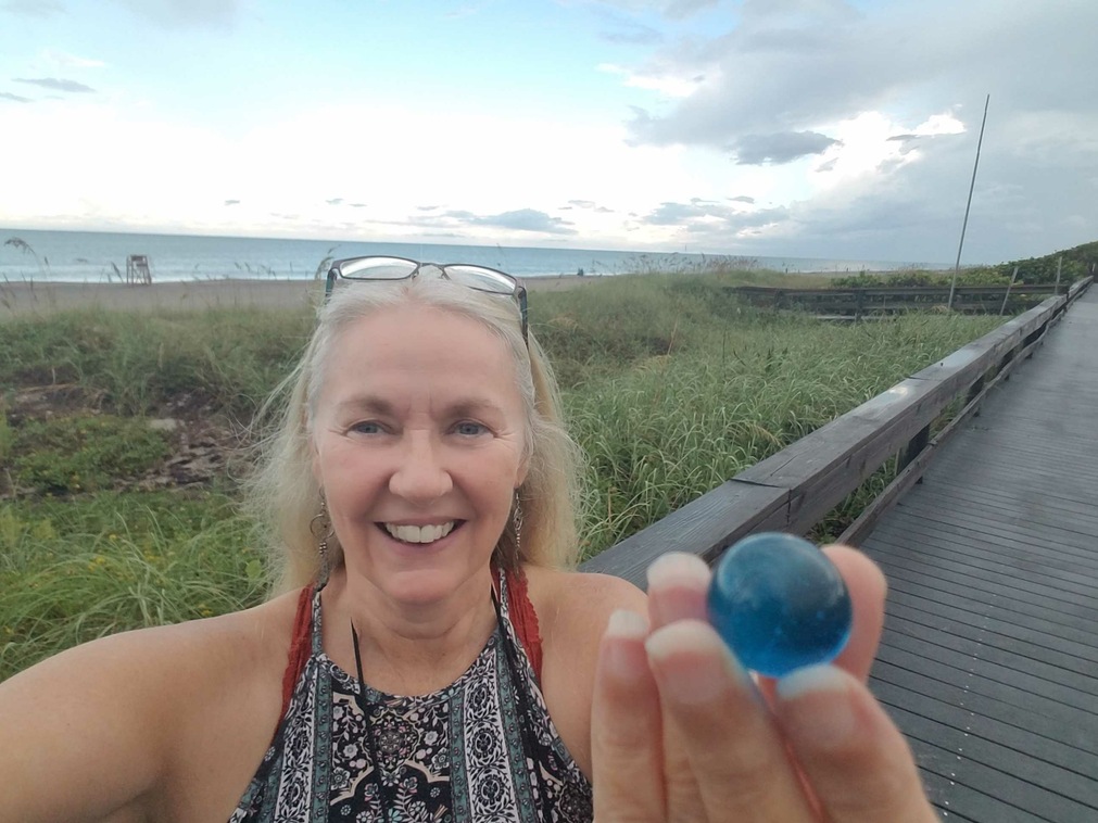 Margaret Warren on the Melbourne Florida Beach boardwalk with a blue marble and with the Atlantic ocean in the background.