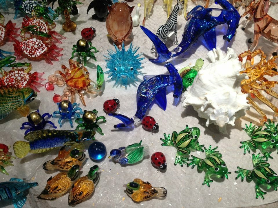 One blue marble is surrounded by a colorful collection of glass animals displayed on a protective bed of white bubble wrap.