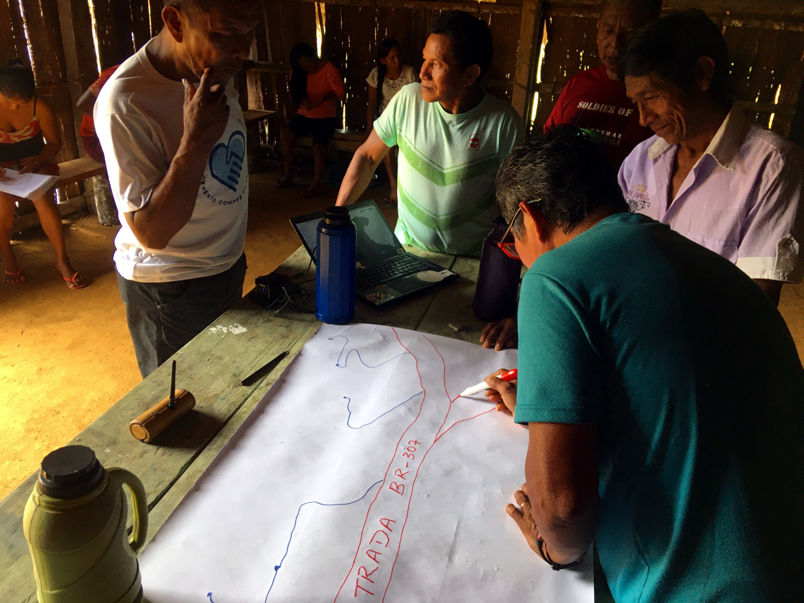 Photo of people gathering over a table and drawing a map