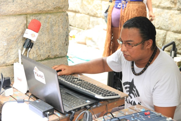 A photo of a person using a computer to run a community radio